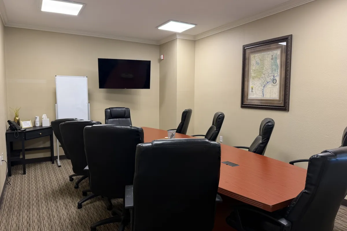 Longhorn meeting room with a conference table, whiteboard and wall-mounted TV at Heritage Office Suites Georgetown