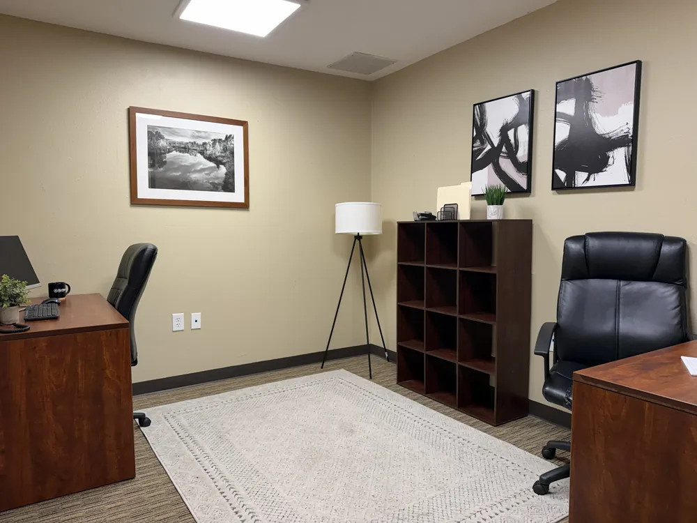 Furnished private office with a desk, bookshelf and armchair at Heritage Office Suites Georgetown