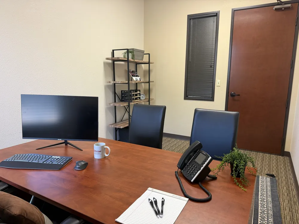 Private office with a desk, monitor, phone and two guest chairs at Heritage Office Suites Round Rock