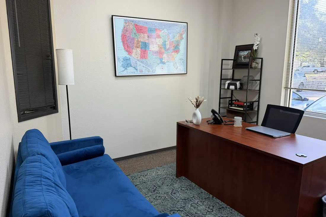 Furnished private office with a desk and a blue sofa at Heritage Office Suites Round Rock