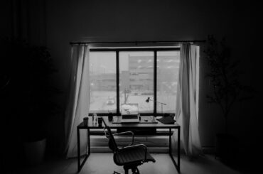 Empty office desk and rolling chair in front of a window with soft light.